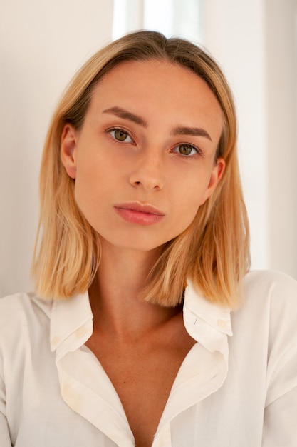 Portrait photo of a young woman on a white background. Woman in white shirt by the window