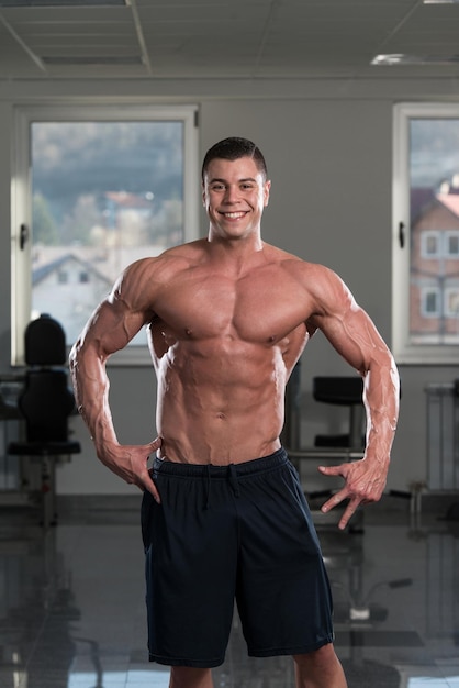 Портрет физически здорового мужчины, показывающего свое хорошо тренированное тело в спортзале
