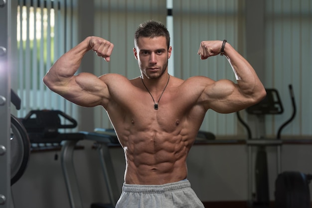 Портрет физически здорового молодого человека, напрягающего мышцы