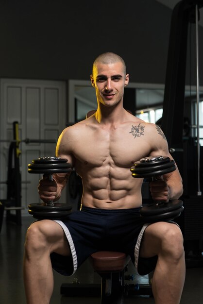 Portrait Of A Physically Fit Young Man In A Healthy Club With Dumbbells