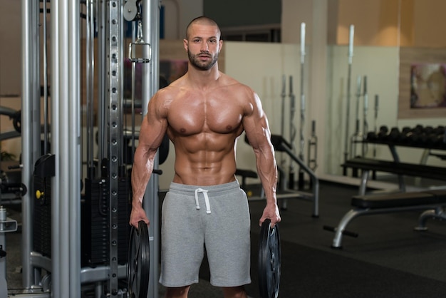 Portrait Of A Physically Young Man Holding Weights In Hands