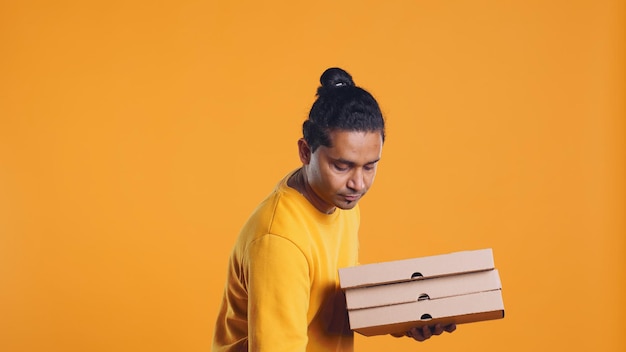 portrait of pizza delivery man holding takeaway boxes studio background