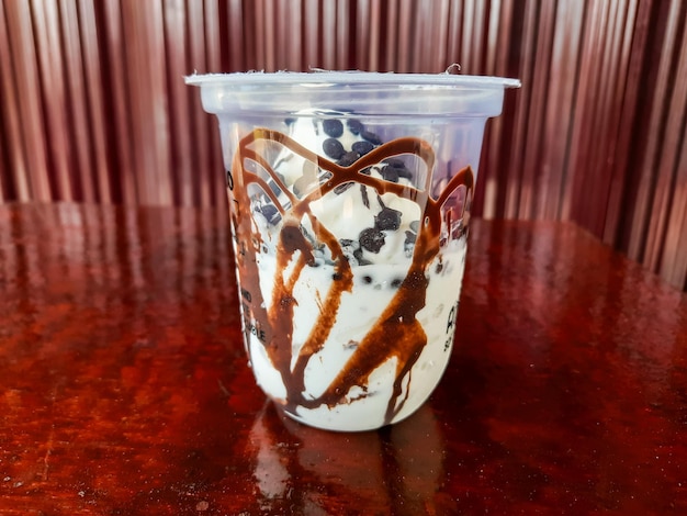 Photo portrait of a plastic cup ice cream drink with vanilla flavor and chocolate chip topping