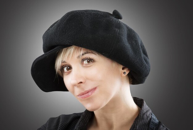 Portrait of a playful girl in black cap studio shot gray background