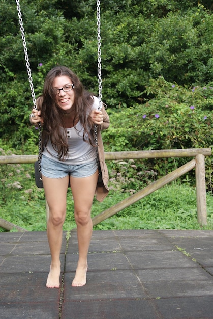 Photo portrait of playful young woman swinging at park