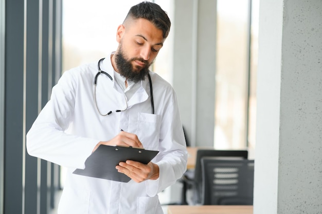 Portrait of pleasant young Arabian doctor in white coat