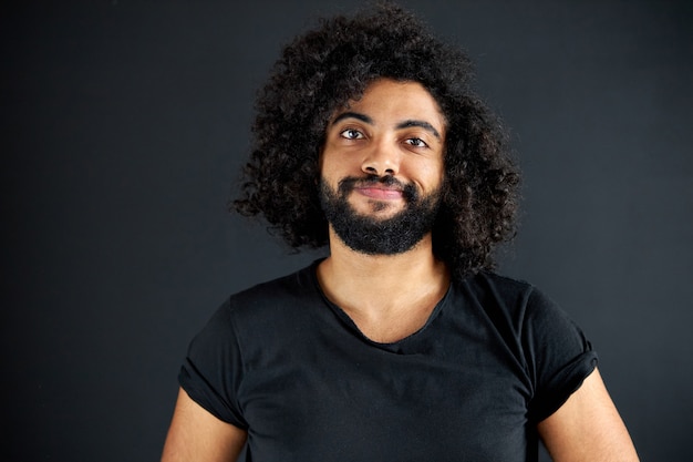 Portrait of pleased arab man isolated in studio, handsome guy in casual wear posing