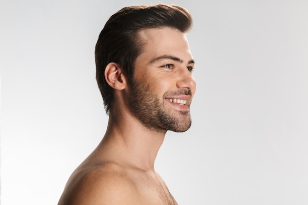 Portrait of pleased half-naked man smiling and looking aside isolated on white