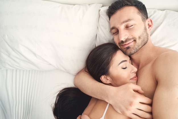 Portrait of a pleased young man and his serene wife sleeping in each others arms