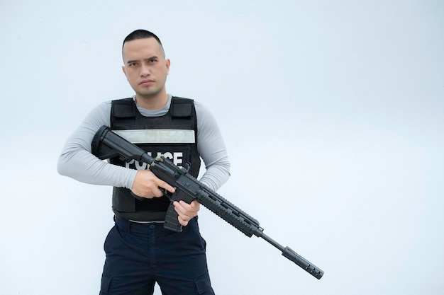 Foto ritratto di polizia tenere la pistola in mano su sfondo bianco bel poliziotto asiatico