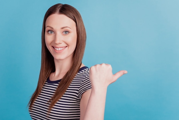 Portrait of positive adviser girl indicate thumb empty space toothy smile on blue background