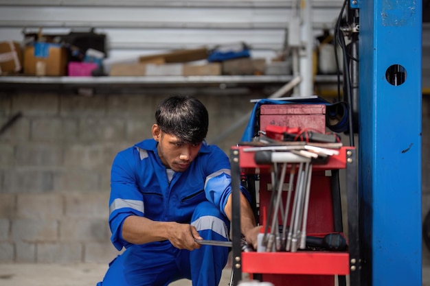 Portrait of positive asian auto mechanic in uniform posing after work he is keen on repairing cars automobiles