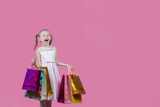 Photo portrait of positive caucasian girl have fun on free time holding colorful bags addicted shopper bargains over pink color background with copy space.