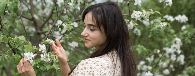 Ritratto di una ragazza bruna allegra positiva in un parco di primavera verde.