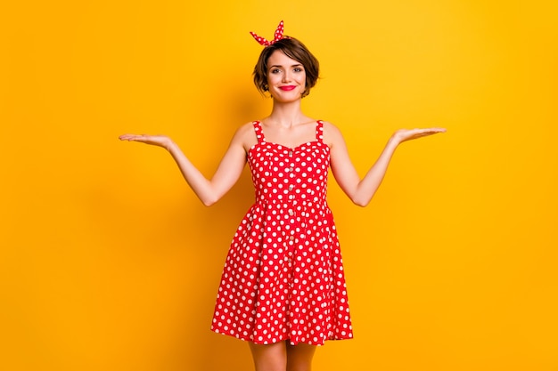 Portrait of positive cheerful girl hold hand display ads promotion recommend suggest select offer object wear red polka-dot skirt isolated over shine color wall