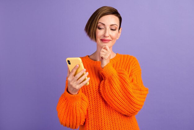 Portrait of positive cheerful girl use smart phone share social media news wear style stylish trendy jumper isolated over purple color background