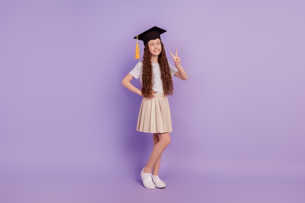 Portrait of positive cheerful lovely cute student girl show v-sign on purple background