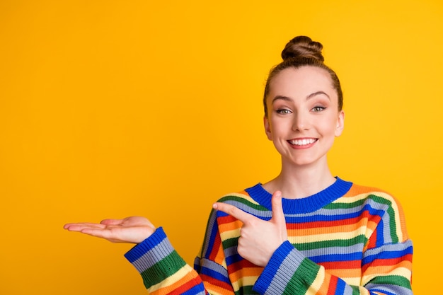 Portrait of positive cheerful promoter girl point index finger copyspace hand recommend choose decide advise promo ads wear sweater isolated over bright color background