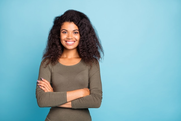 Портрет позитивной уверенной темнокожей девушки, истинного работника в большой компании, готовой решить сложный вопрос, перекрестные руки носят зеленый свитер в стиле, изолированном на стене синего цвета