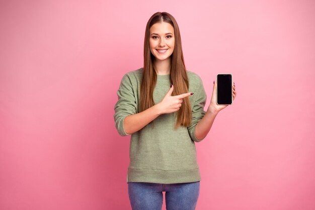 Portrait of positive girl hold smartphone point finger demonstrate