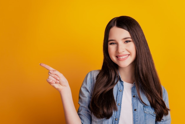 Portrait of positive girl point index finger copyspace isolated over yellow color background