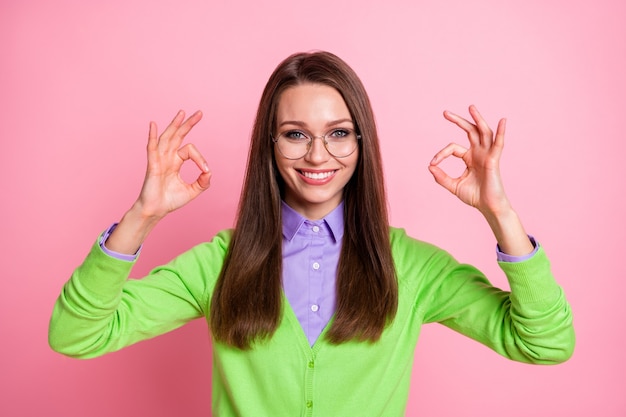 Il ritratto della ragazza positiva mostra il segno giusto isolato sopra il fondo di colore pastello