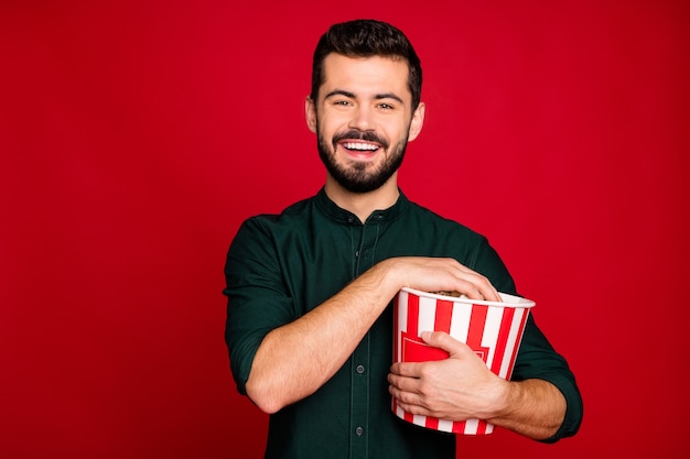 Portrait of positive guy have break pause watch funny movie hold big red striped pop corn box enjoy recreation wear casual style clothes 