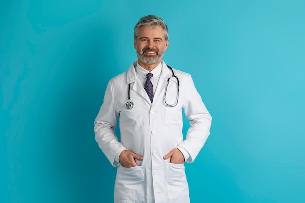 Portrait of positive handsome european doctor posing on blue