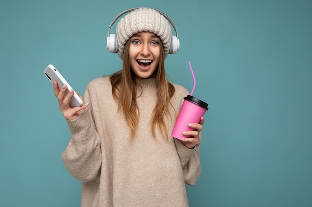 Portrait of positive happy young beautiful blonde woman with sincere emotions wearing beige pullover