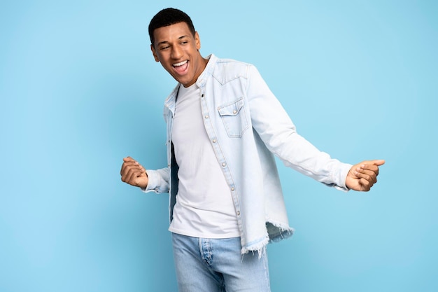 Portrait of positive inspired brunette man dancing and rejoicing alone