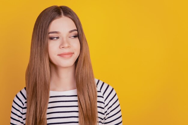 Portrait of positive lady look side empty space smile on yellow background
