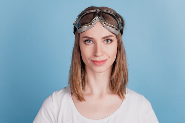 Il ritratto di una signora sicura adorabile adorabile positiva indossa occhiali sportivi su sfondo blu