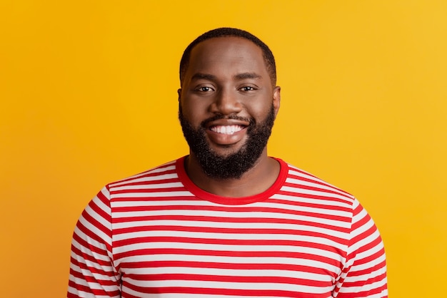 Portrait of positive man calm look camera toothy smile on yellow background