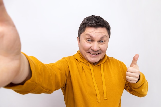 Photo portrait of positive man making selfie pov expressing happiness showing thumb up to camera