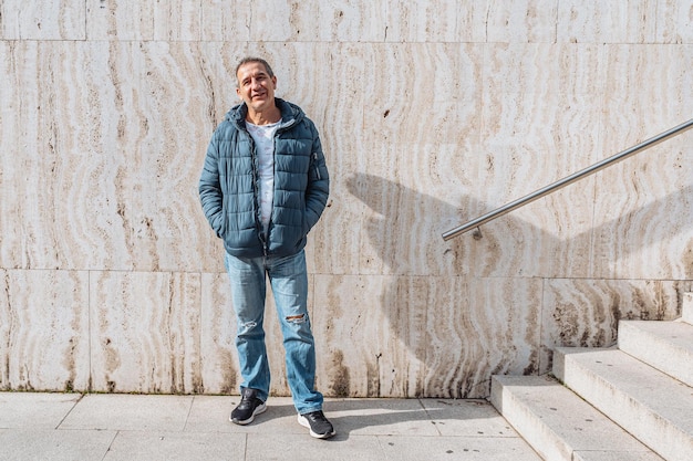 Portrait positive middleaged man against background marble wall with steps