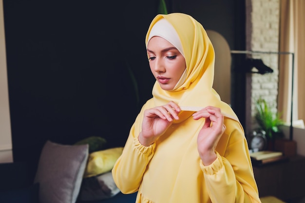 Portrait of positive pretty young arabian woman in pink headscarf touching face with hand