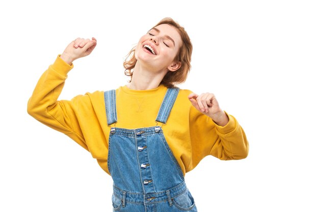 Портрет позитивной рыжей девушки в повседневных джинсах эмоционально радуется и чувствует себя счастливой на белом фоне рекламного баннера