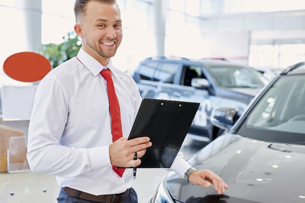 Portrait of positive smiling caucasian man consultant in dealership