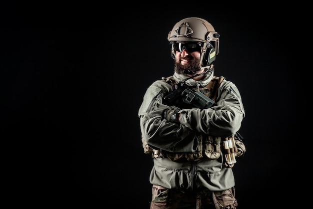 Portrait of a positive soldier in a military uniform a commando is smiling on a black background