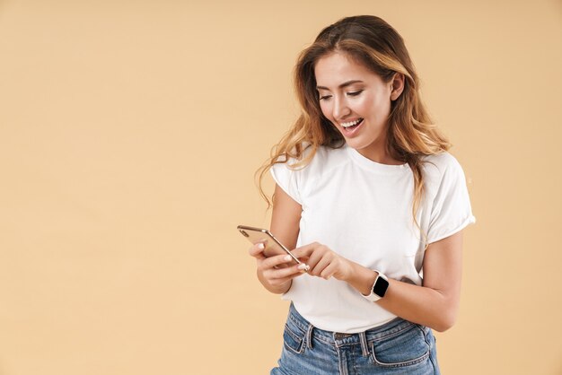 Portrait of positive woman smiling while holding cellphone isolated