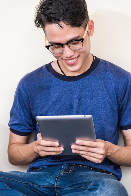 Portrait of positive young man student sitting using with technology digital tablet reading electronic book at university or college, men browsing internet, studying online with gadget