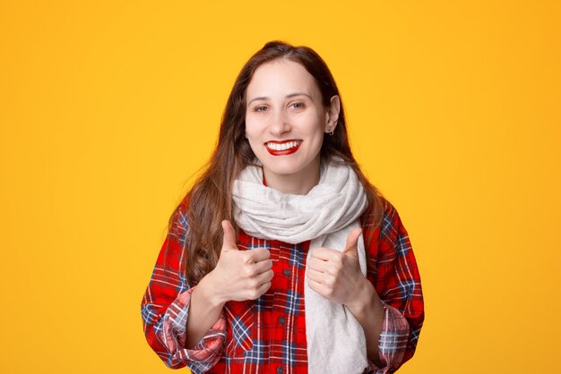 Portrait of positive young woman wearing scarf and showing thumbs up gesture