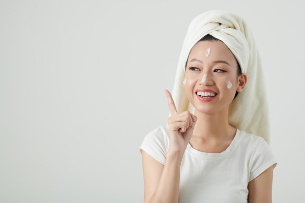 Portrait of positive young woman with rich moisturizer on her face