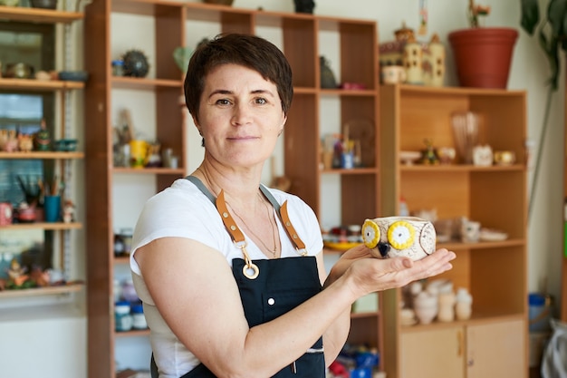 Ritratto di una donna maestra di ceramica che mostra il lavoro finito.