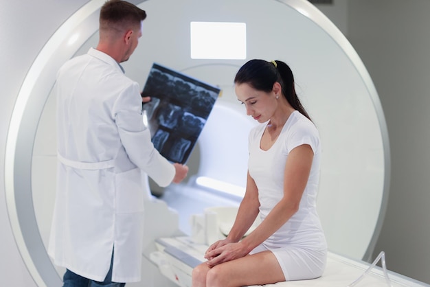 Portrait of practitioner looking at mri picture female patient\
at medical consultation magnetic