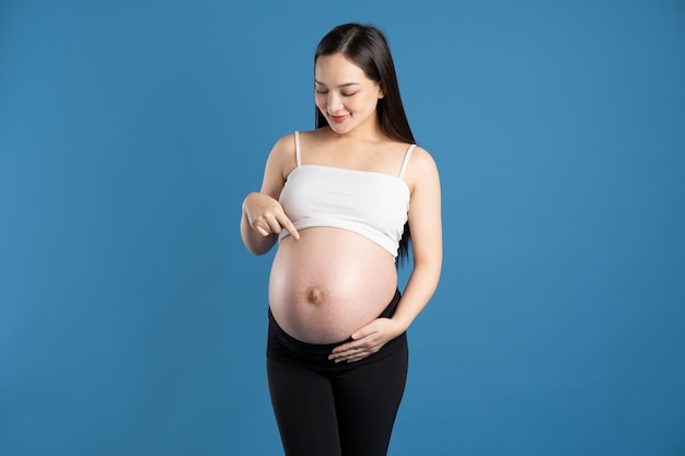 Portrait of pregnant asian woman isolated on blue background