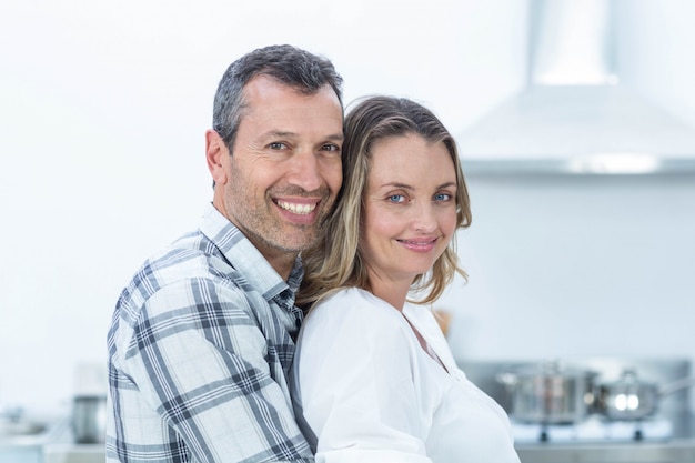 Portrait of pregnant couple looking at camera in kitchen