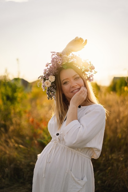 Portrait of a pregnant woman a beautiful young pregnant woman in a white dress walks in the field