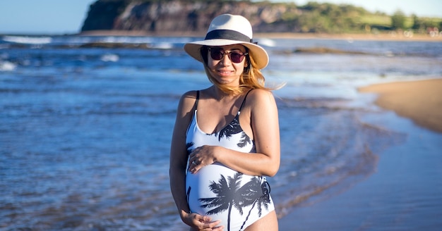 해변에서 수영복 지주 배꼽에 임신 한 여자의 초상화
