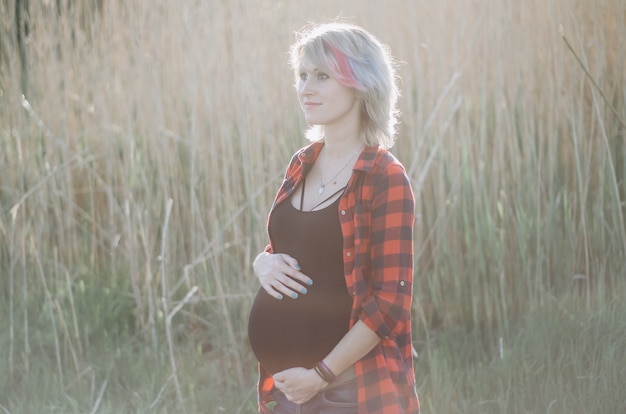 Portrait of pregnant young woman outdoors in warm summer day